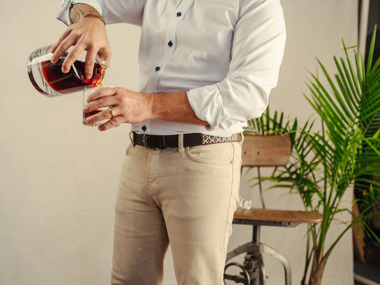 A dark brown leather belt featuring a navy blue and beige geometric woven pattern with red stitching.