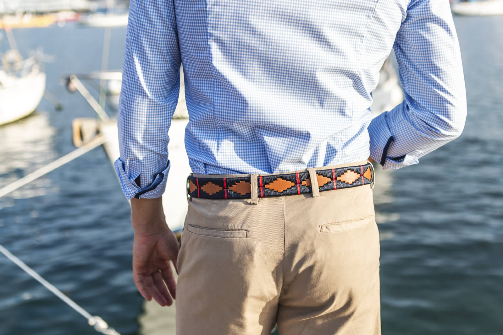 A brown leather belt with a red and deep navy woven geometric pattern and solid brass buckle.