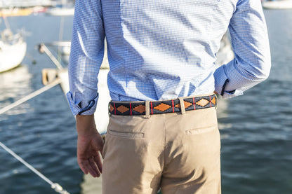 A brown leather belt with a red and deep navy woven geometric pattern and solid brass buckle.
