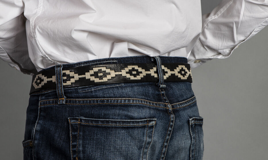 A black leather belt with a white woven geometric pattern and solid brass buckle.