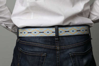 A brown leather belt with a light blue and beige woven pattern and metal nickle buckle.