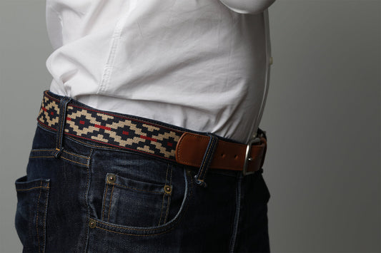 A cognac brown leather belt with a navy, kahki and red woven geometric pattern and solid brass buckle.